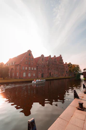 A boat is on the water in front of a large brick building