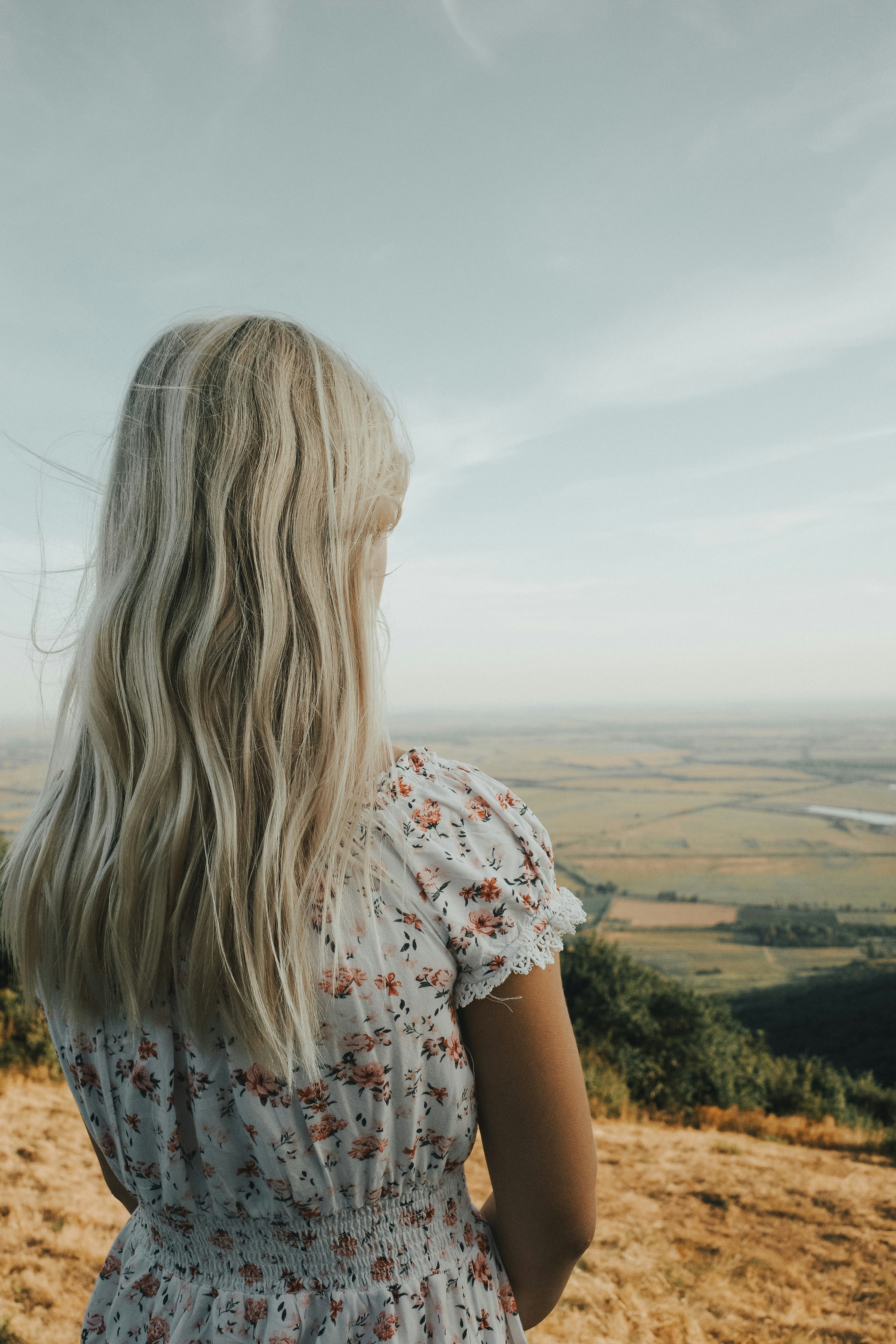 A woman standing on top of a grass covered hillside
