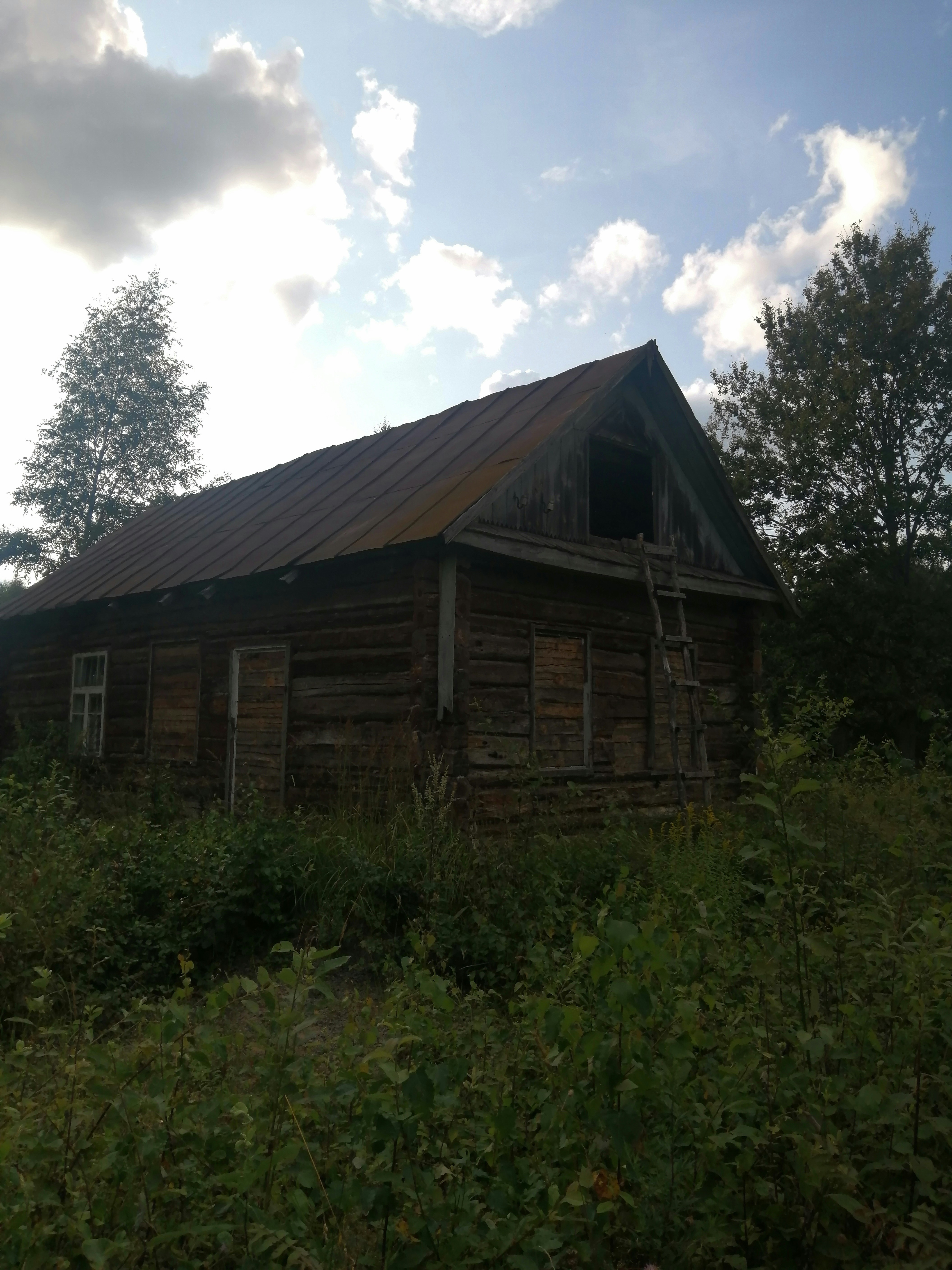An old log cabin sitting in the middle of a field