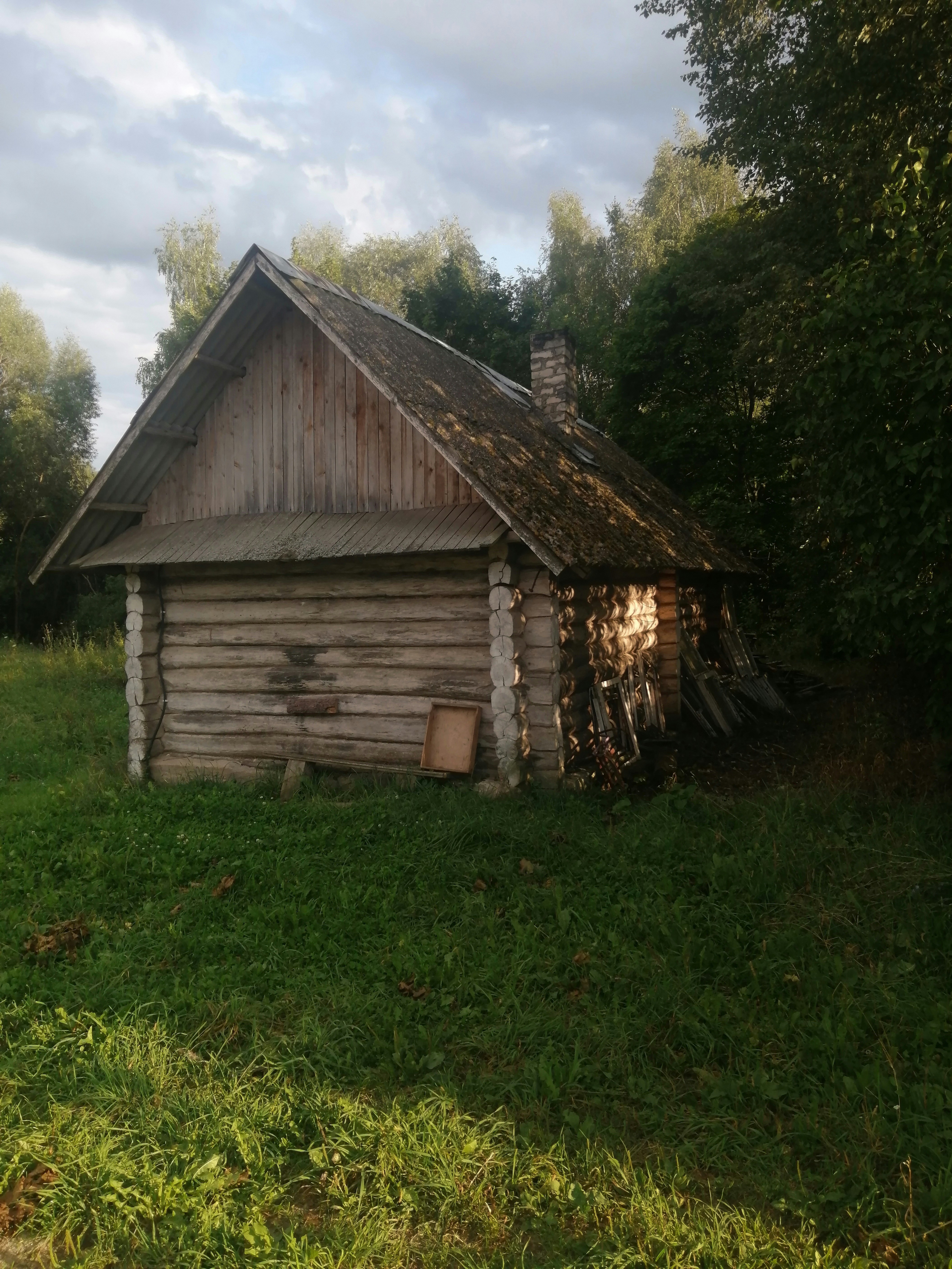 An old log cabin in a grassy field