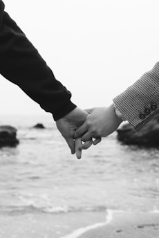 A black and white photo of two people holding hands