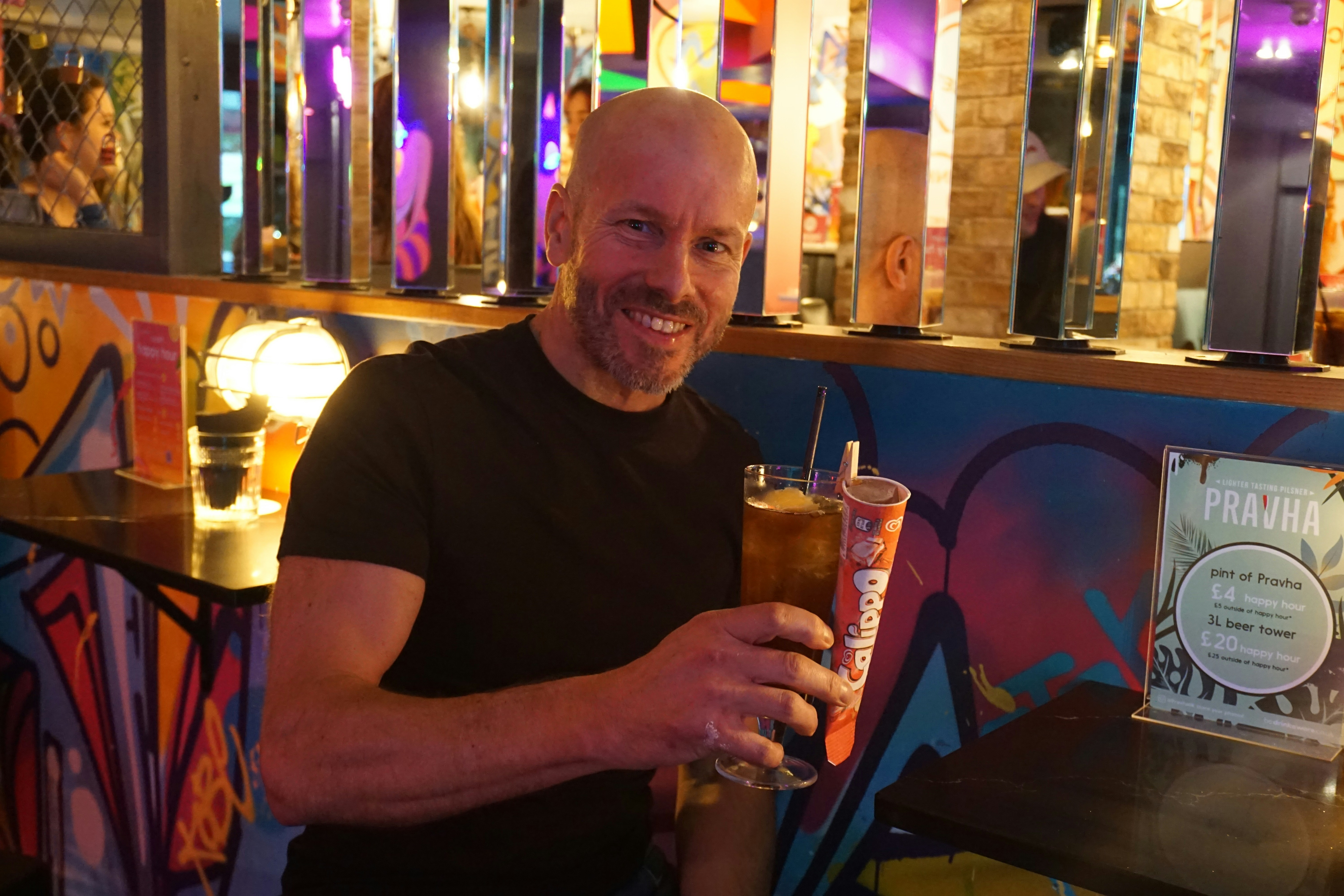 A man sitting at a bar holding a drink