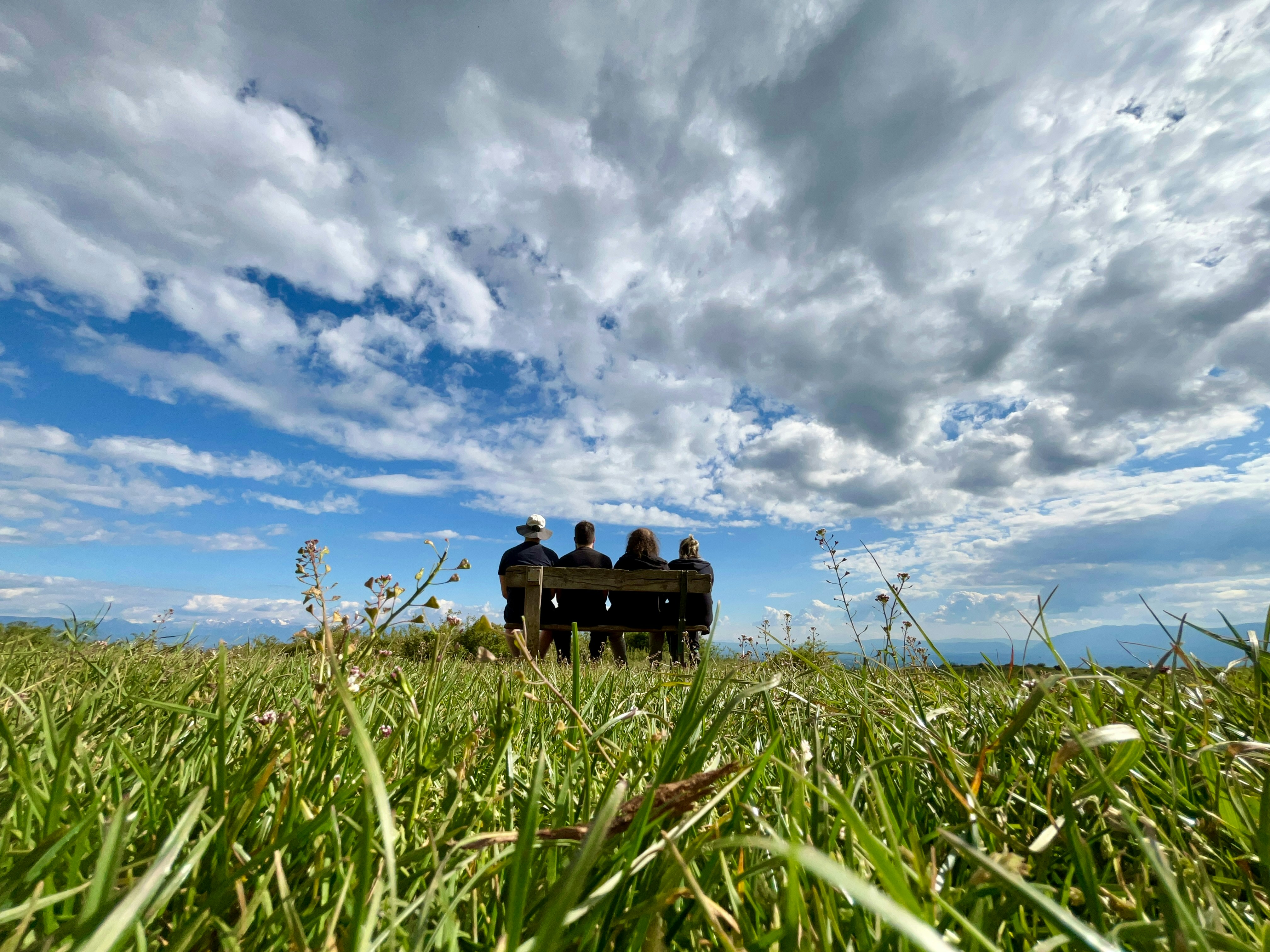 Un gruppo di persone sedute sopra una panchina in un campo