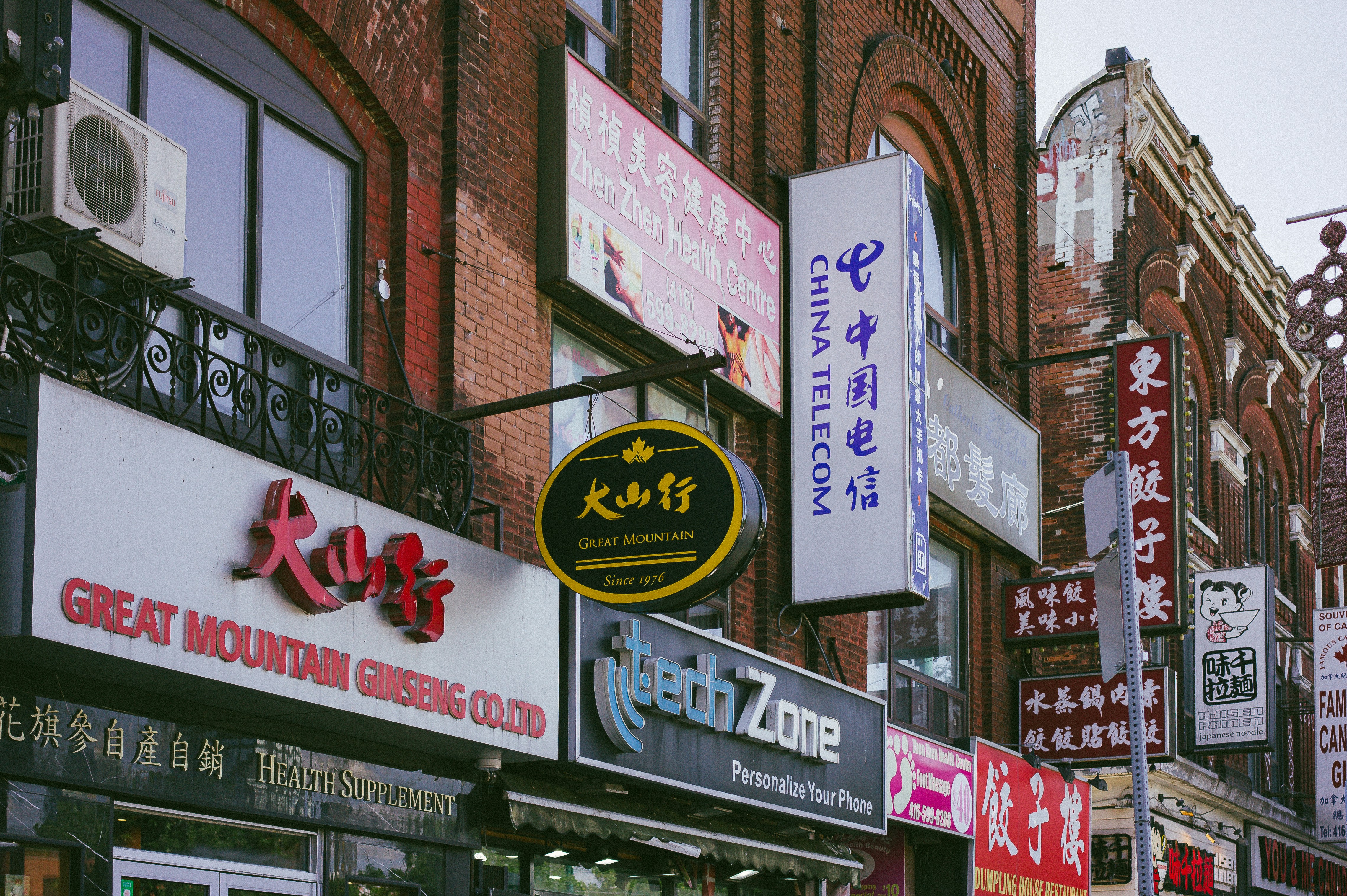 A city street filled with lots of tall buildings, Store signs in Chinatown, Toronto