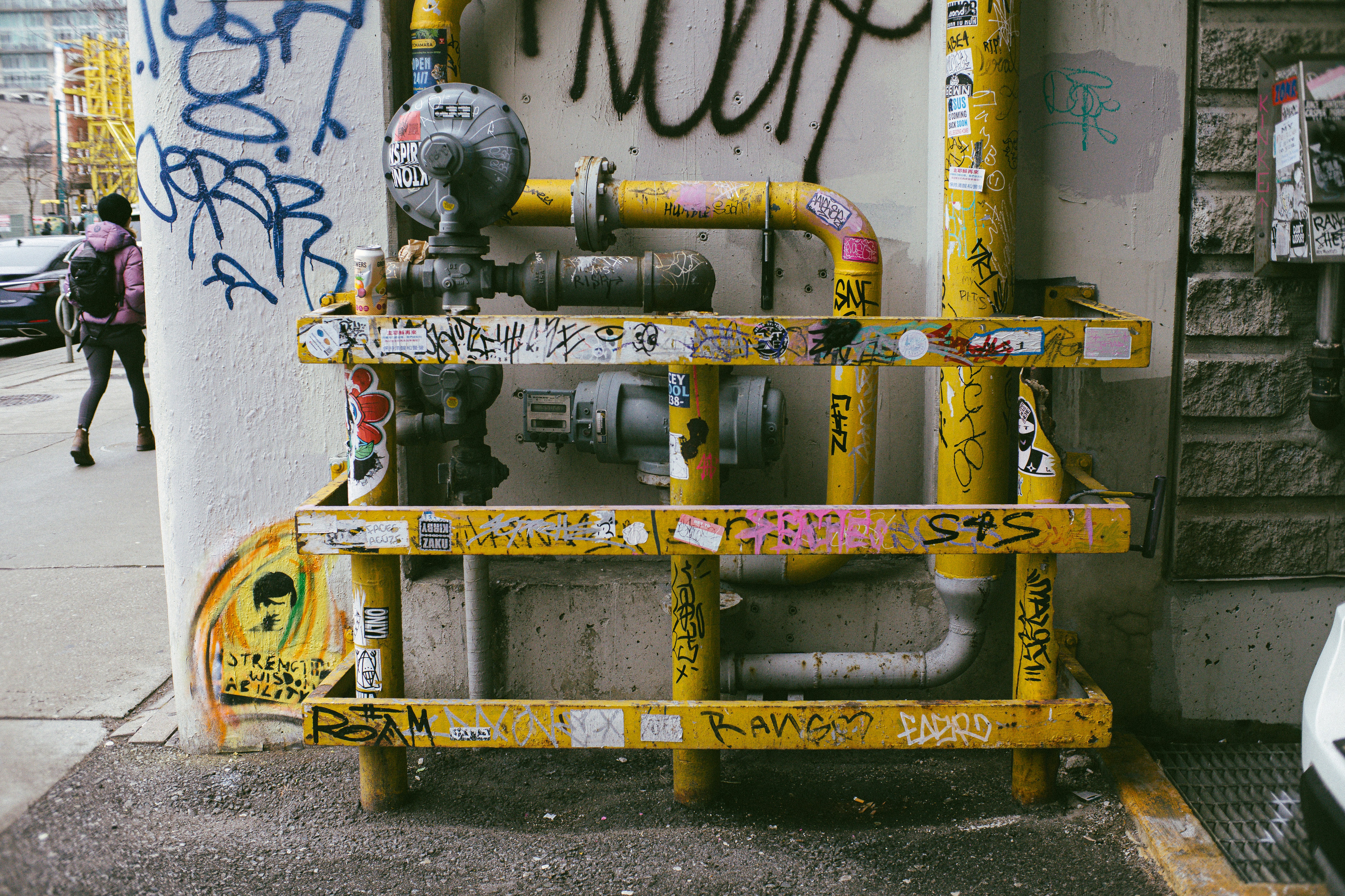 A fire hydrant on the side of a building with graffiti on it