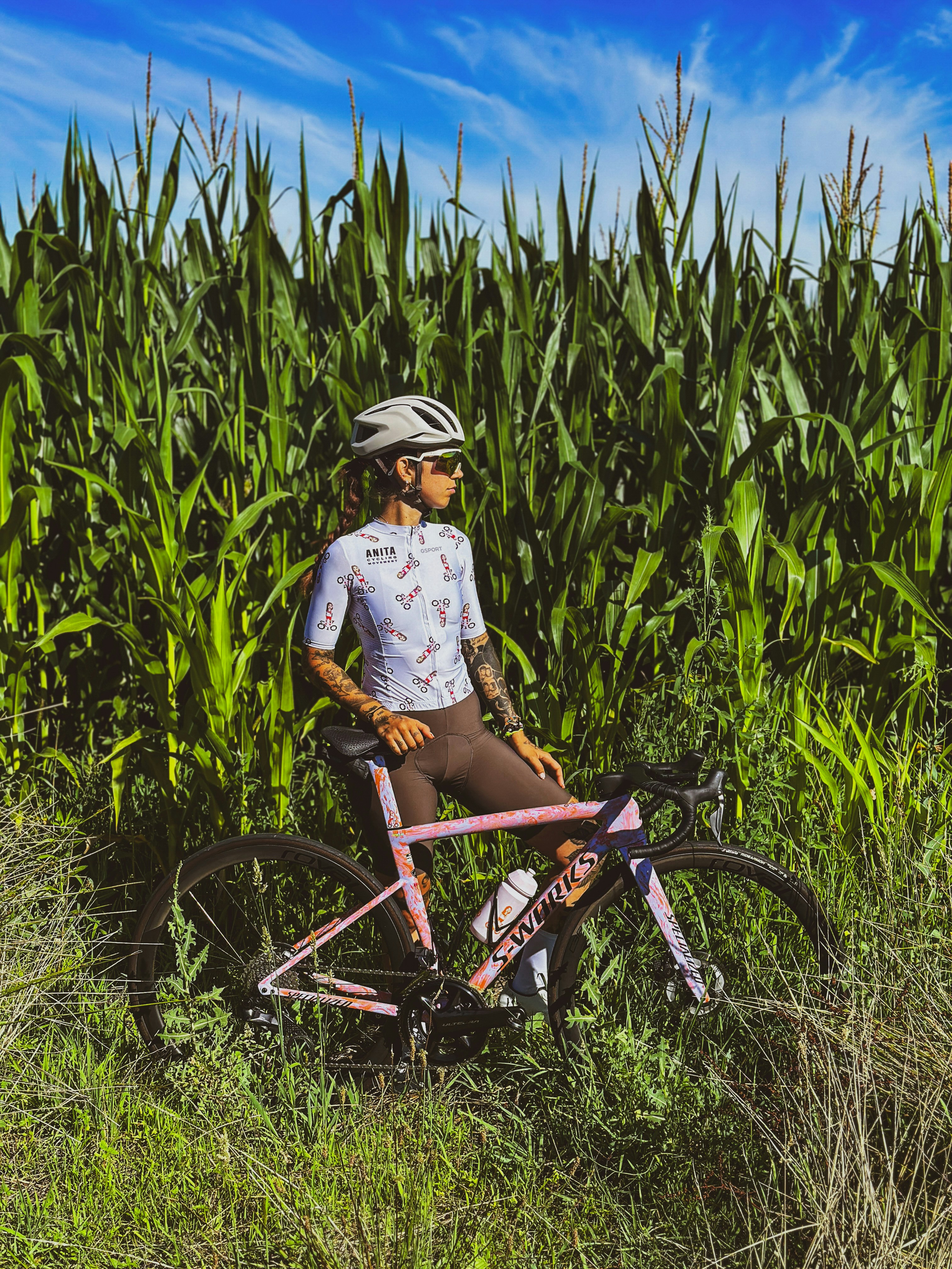 A person standing next to a bike in a field of grass