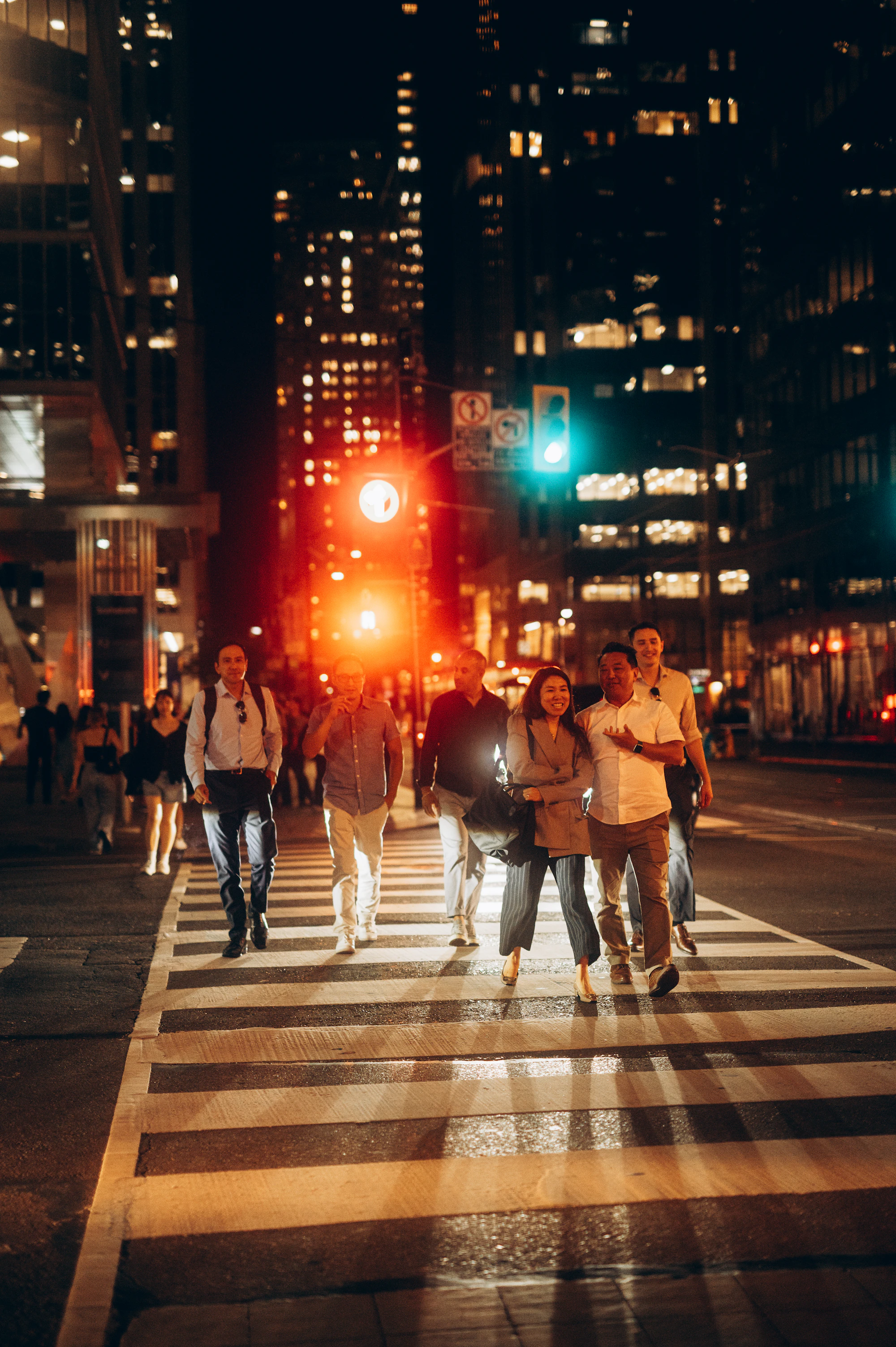 People crossing a busy city street at sunset