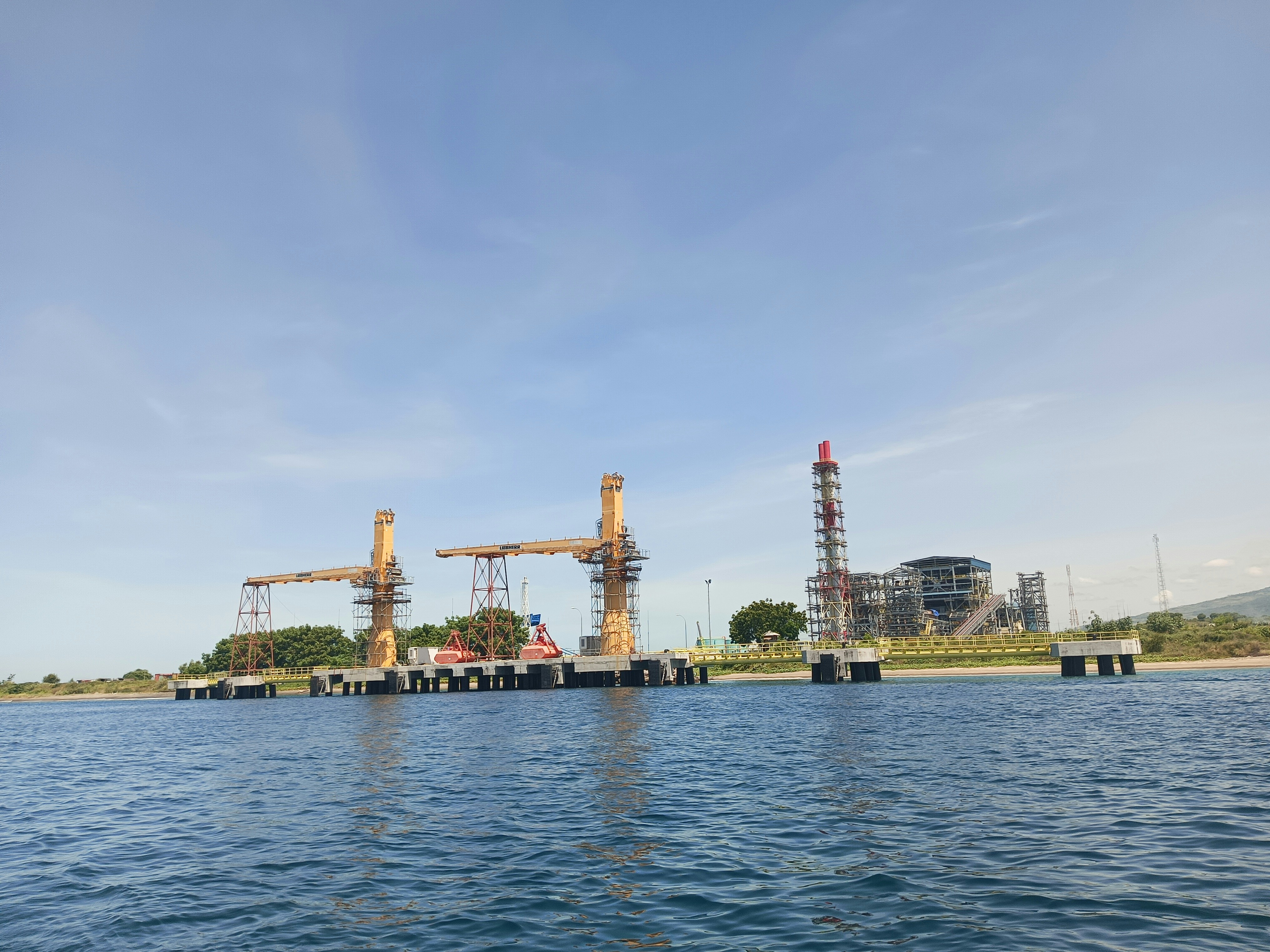 A large body of water with cranes in the background