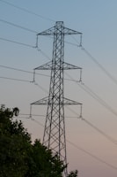 A high voltage power line with trees in the foreground