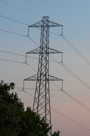 A high voltage power line with trees in the foreground