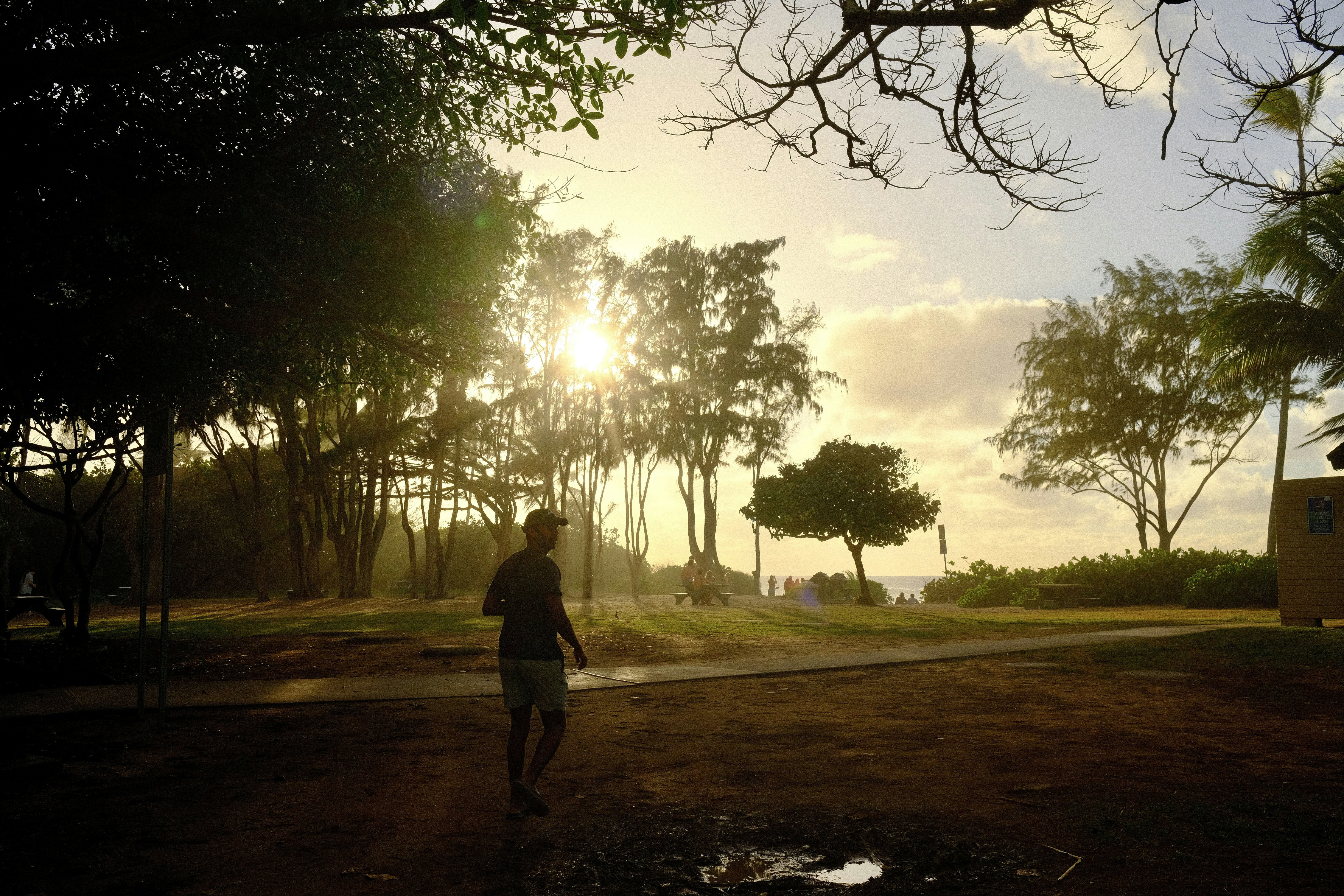 A person walking down a dirt road at sunset
