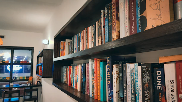 A bookshelf filled with lots of books next to a window