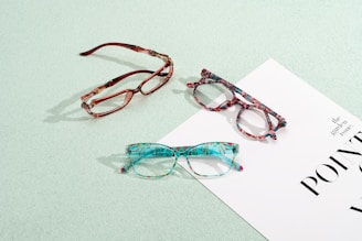 Three pairs of glasses sitting on top of a piece of paper