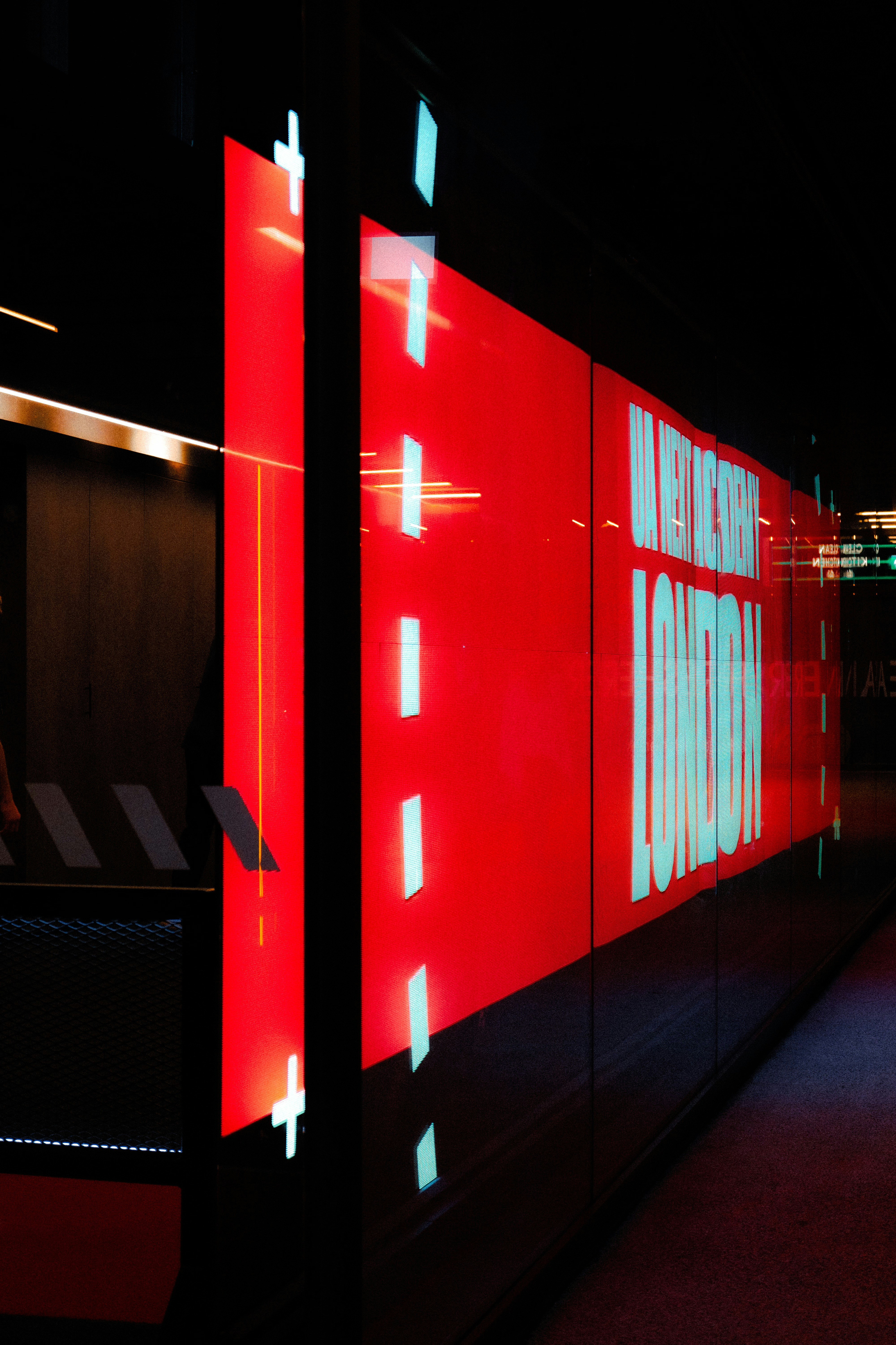 A man walking down a hallway next to a red wall