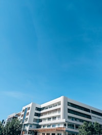A tall white building sitting next to a lush green park