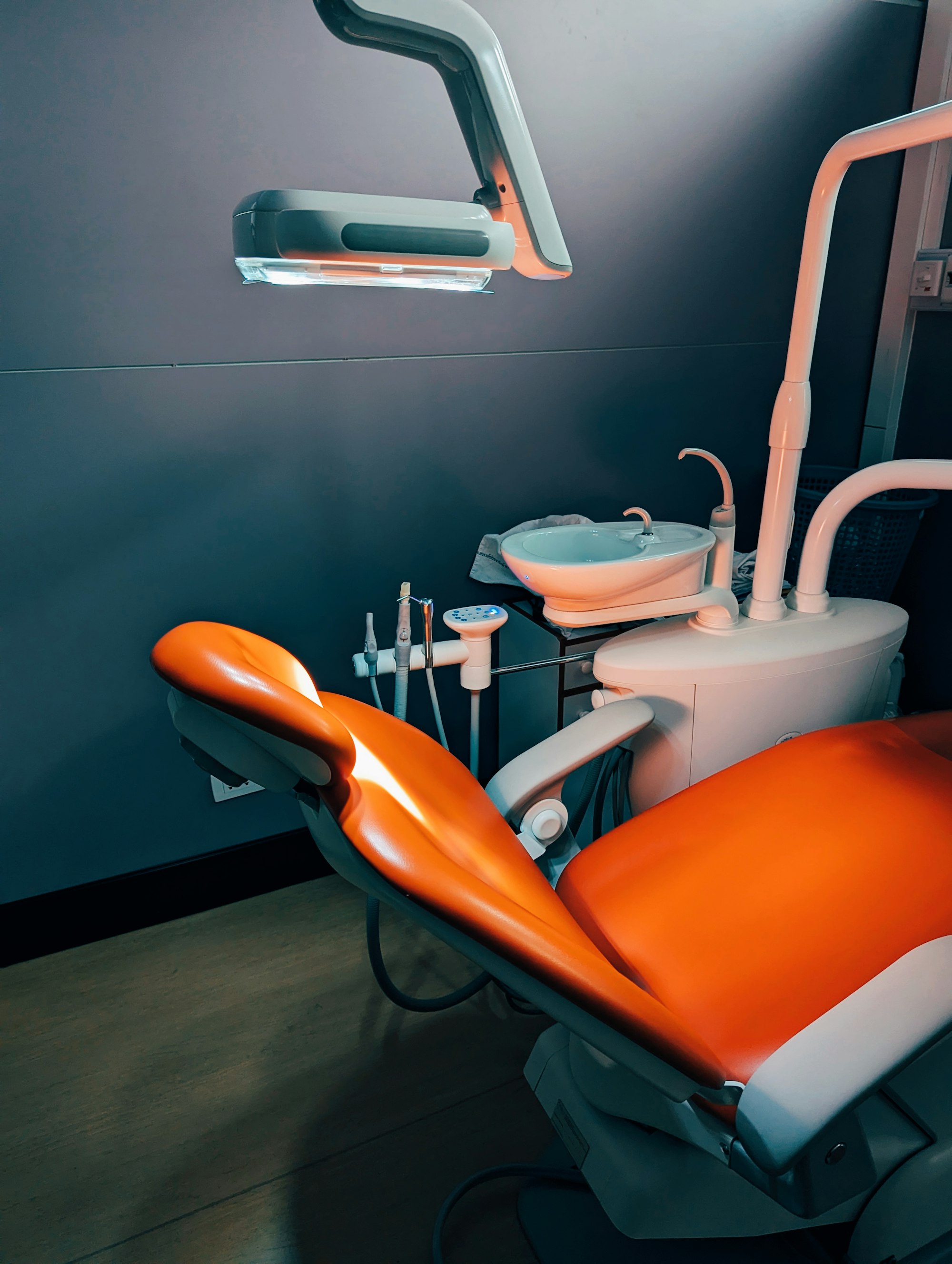An orange dental chair in a dark teal treatment room