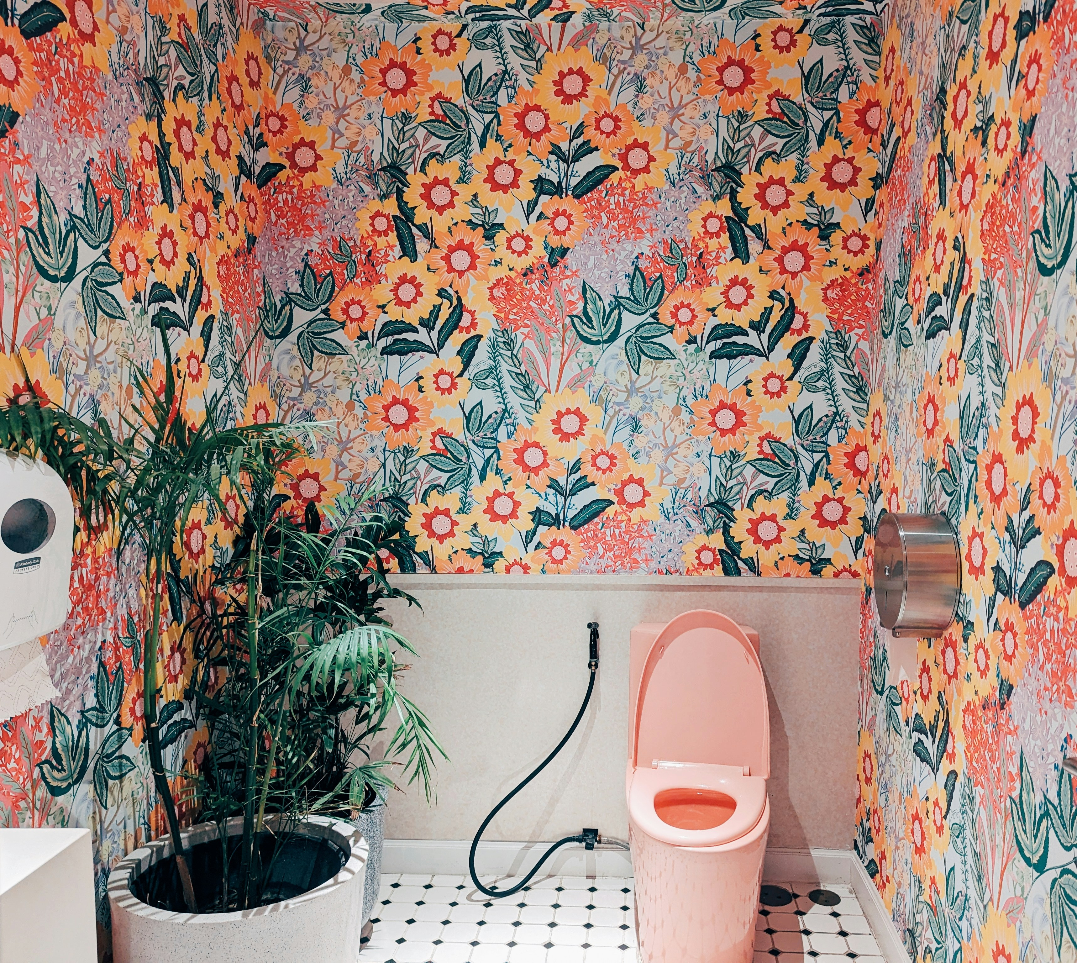 A bathroom with a toilet and a flowered wallpaper