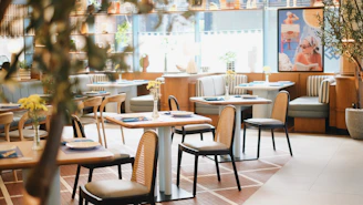 A restaurant with tables, chairs, and plants