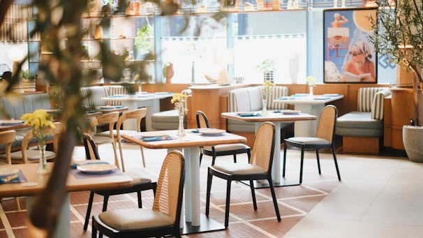 A restaurant with tables, chairs, and plants