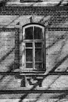 A black and white photo of a brick building with a window