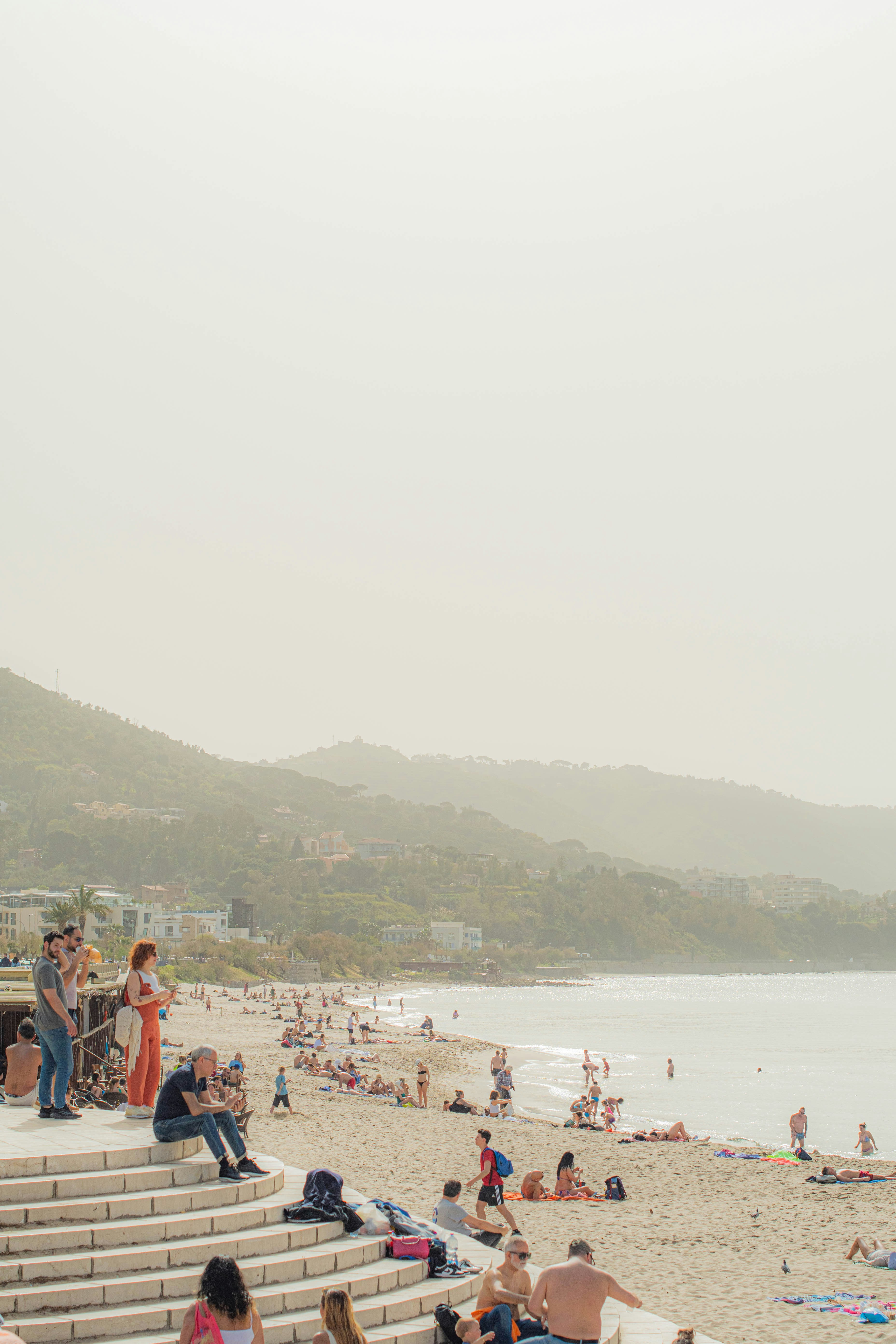 A group of people sitting on top of a sandy beach