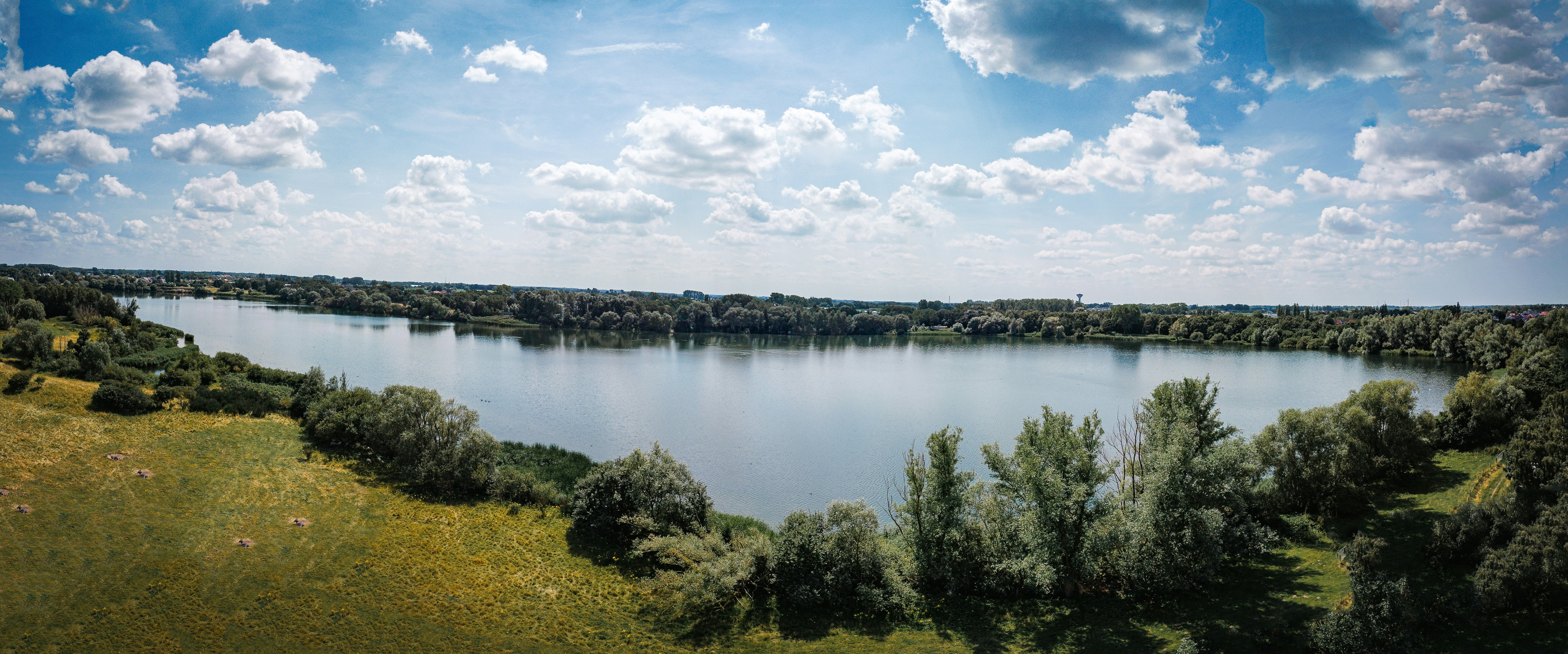 A large body of water surrounded by a lush green field