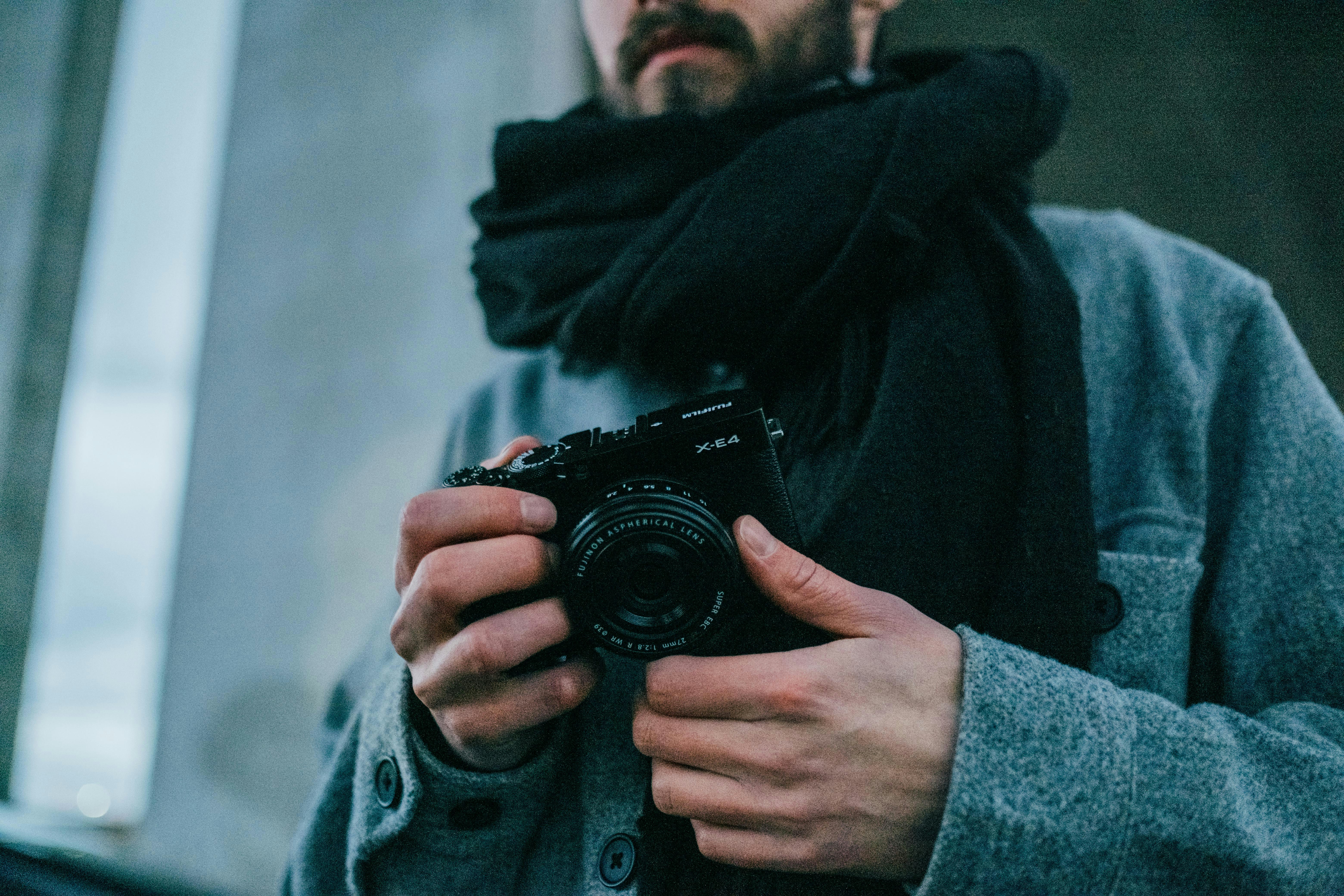 A man holding a camera and wearing a scarf