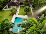 An aerial view of a house with a pool surrounded by palm trees
