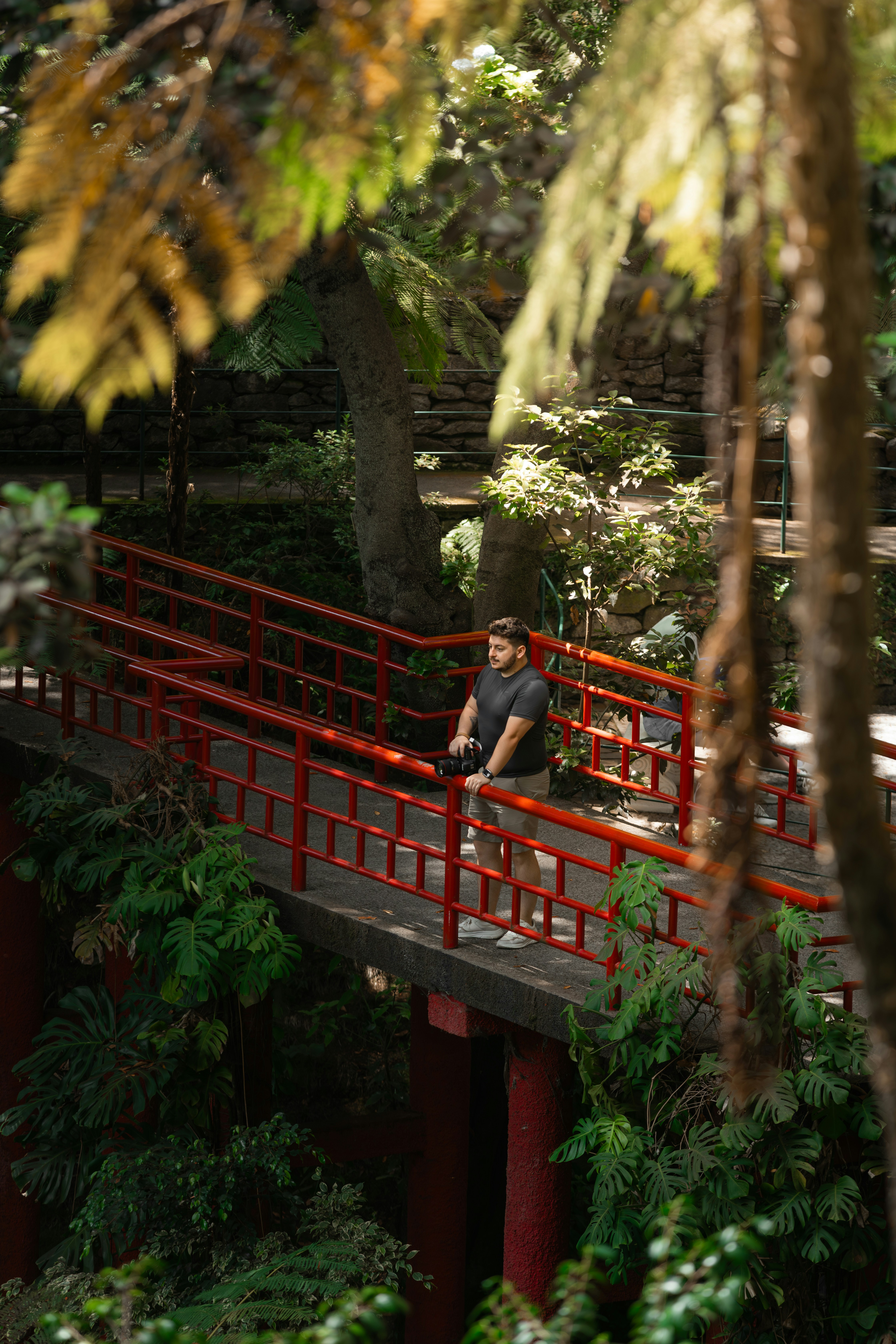 A man is sitting on a red bridge