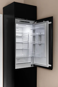 A black refrigerator with its door open in a kitchen
