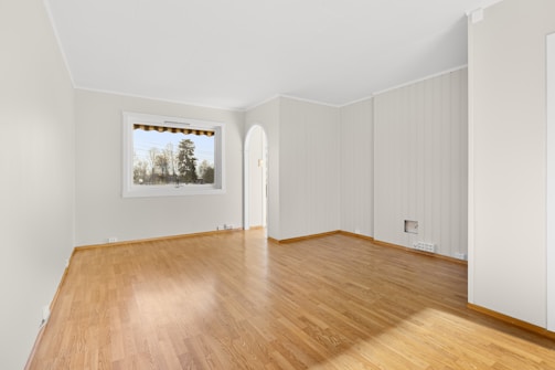 An empty room with hard wood floors and white walls