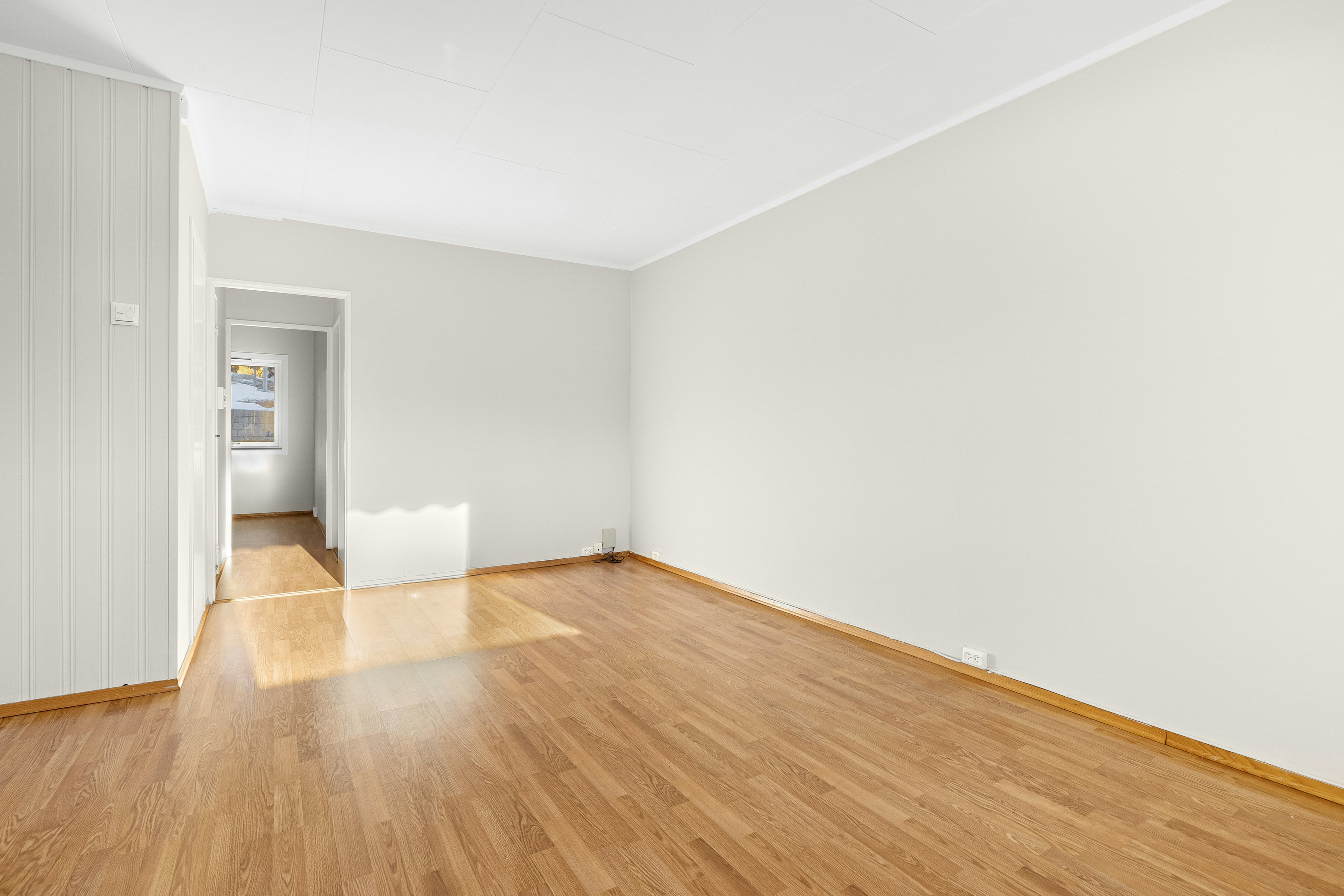 An empty room with hard wood floors and white walls