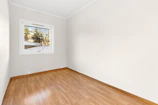 An empty room with hard wood floors and a window