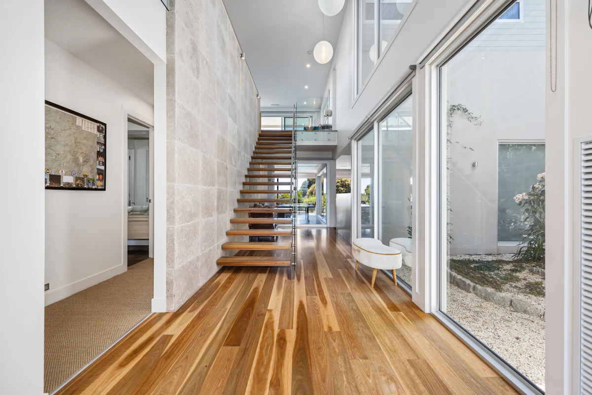 Wide-plank engineered hardwood beside a floating wood staircase.