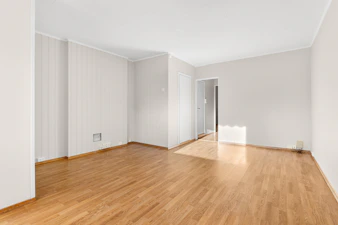 An empty room with hard wood floors and white walls