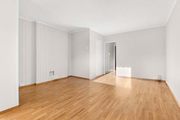 An empty room with hard wood floors and white walls