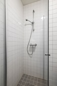 A walk in shower sitting next to a white tiled wall