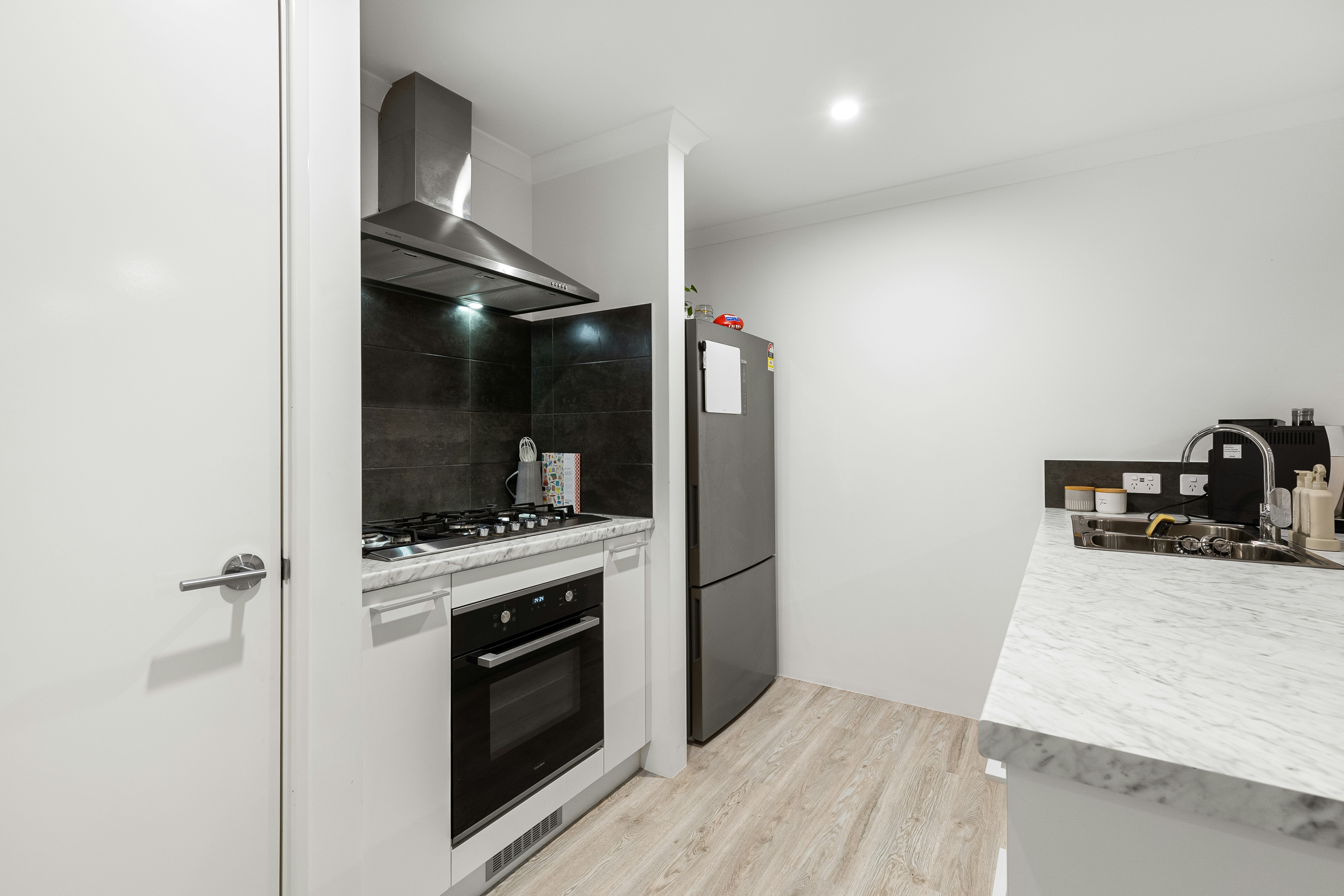 Modern renovated kitchen with white cabinets, marble countertops, and stainless steel appliances