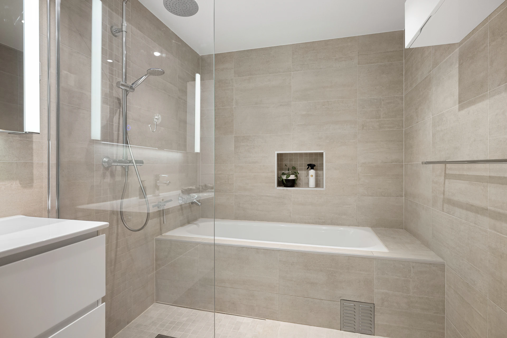 A bathroom with a tub, sink, and mirror
