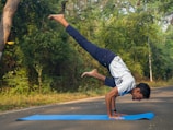 A man doing a handstand on a blue mat