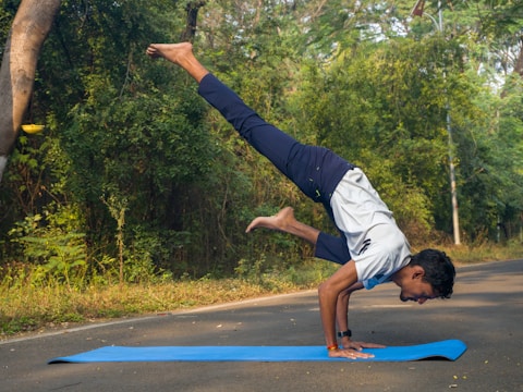 A man doing a handstand on a blue mat