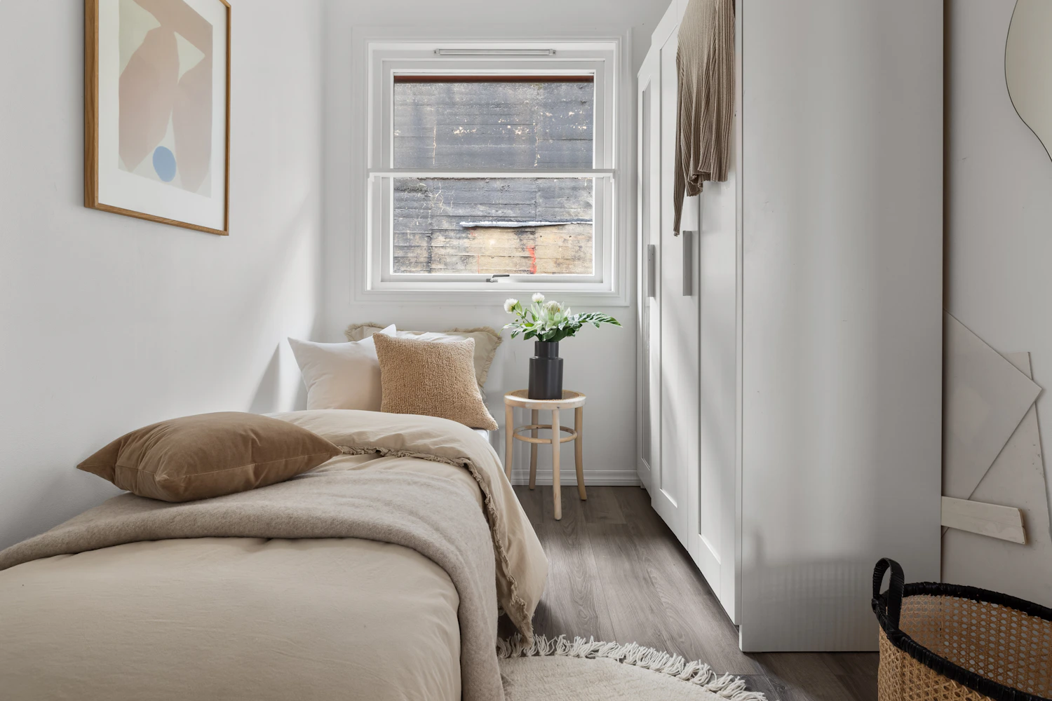 Layered neutral bedding with pillows and textured blanket in a bright bedroom