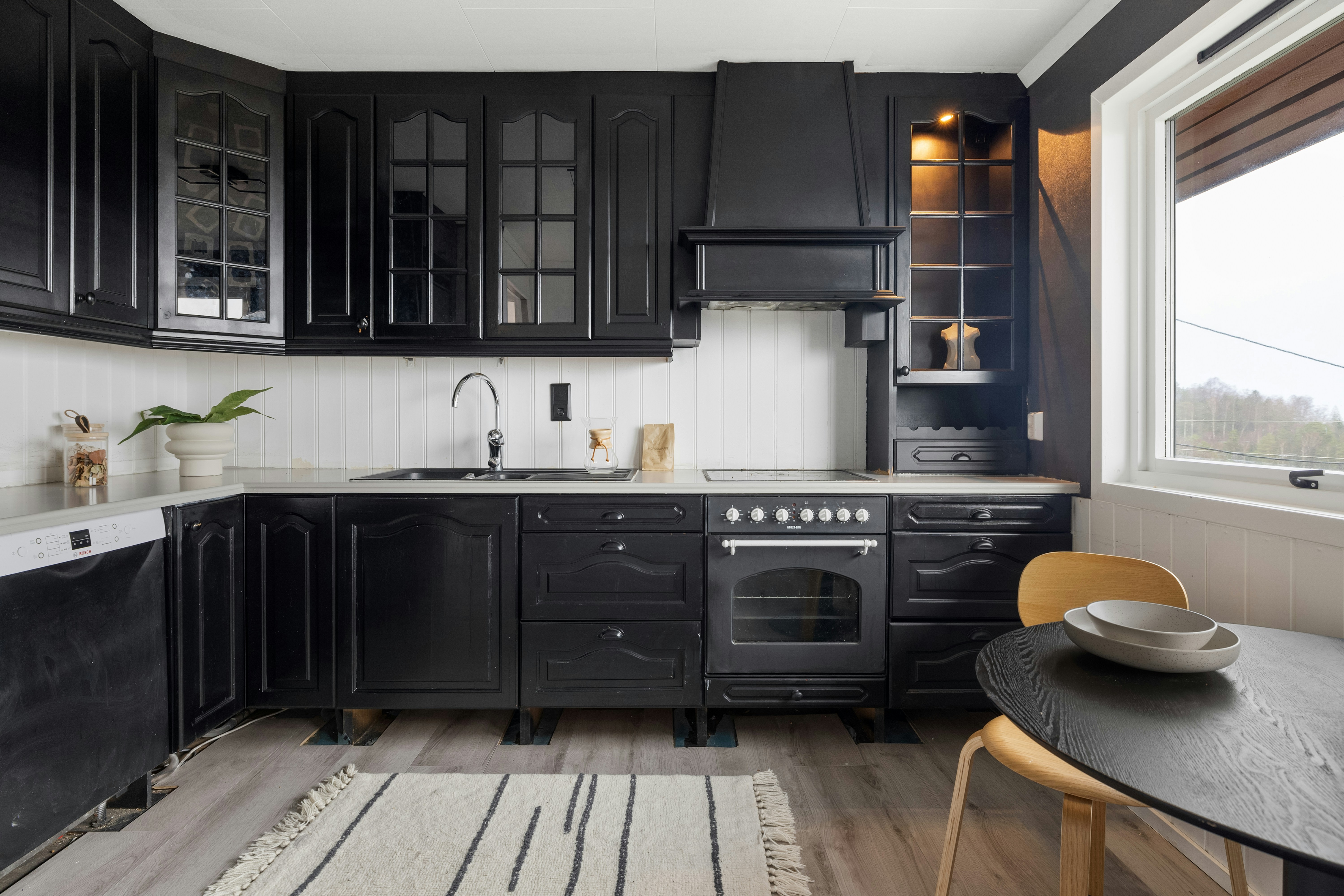 A kitchen with black cabinets and white walls