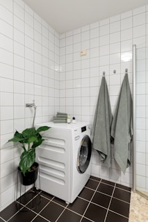 A washer and dryer in a white tiled bathroom