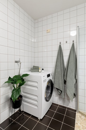 A washer and dryer in a white tiled bathroom