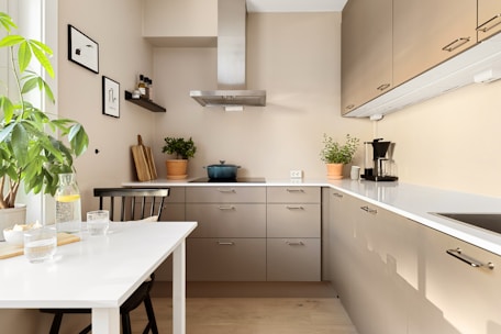A kitchen with a white table and a plant in a vase