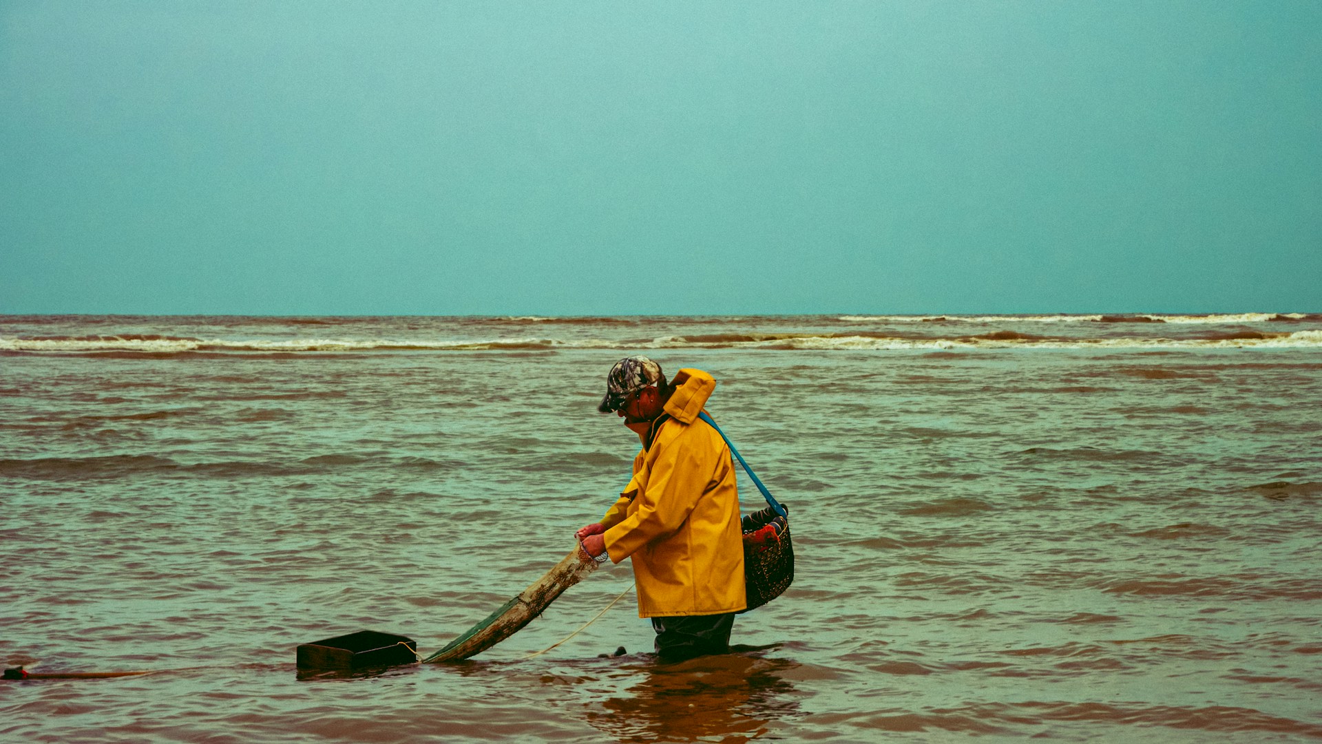 A man standing in the ocean holding a net