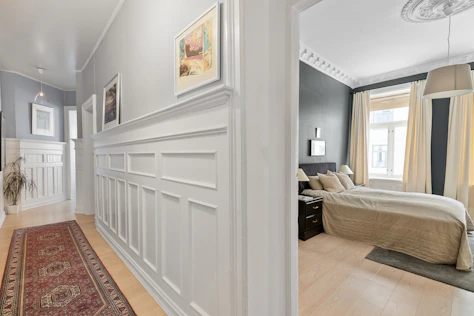 A hallway with a rug and pictures on the wall