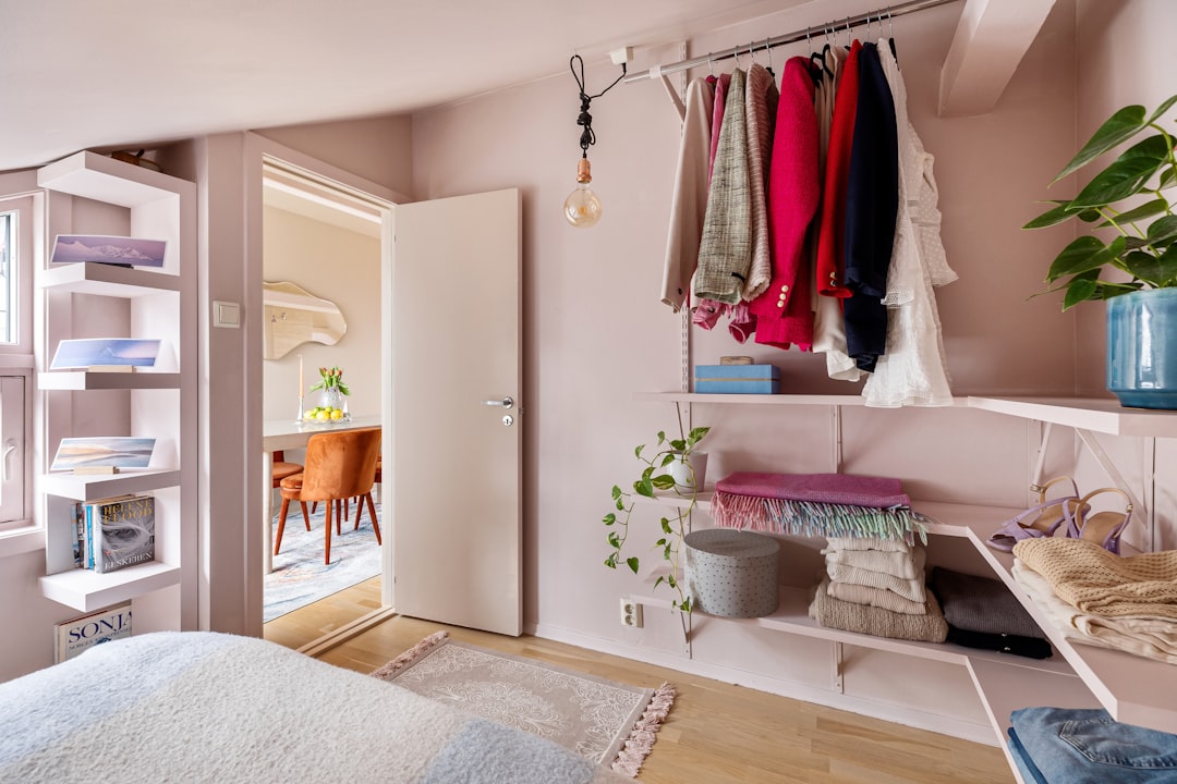open clothing rack with colorful jackets and dresses in a cozy apartment bedroom
