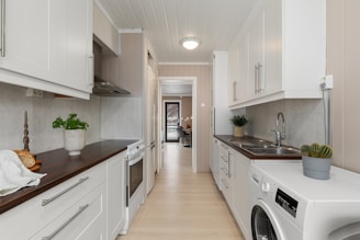 A long narrow kitchen with a washer and dryer